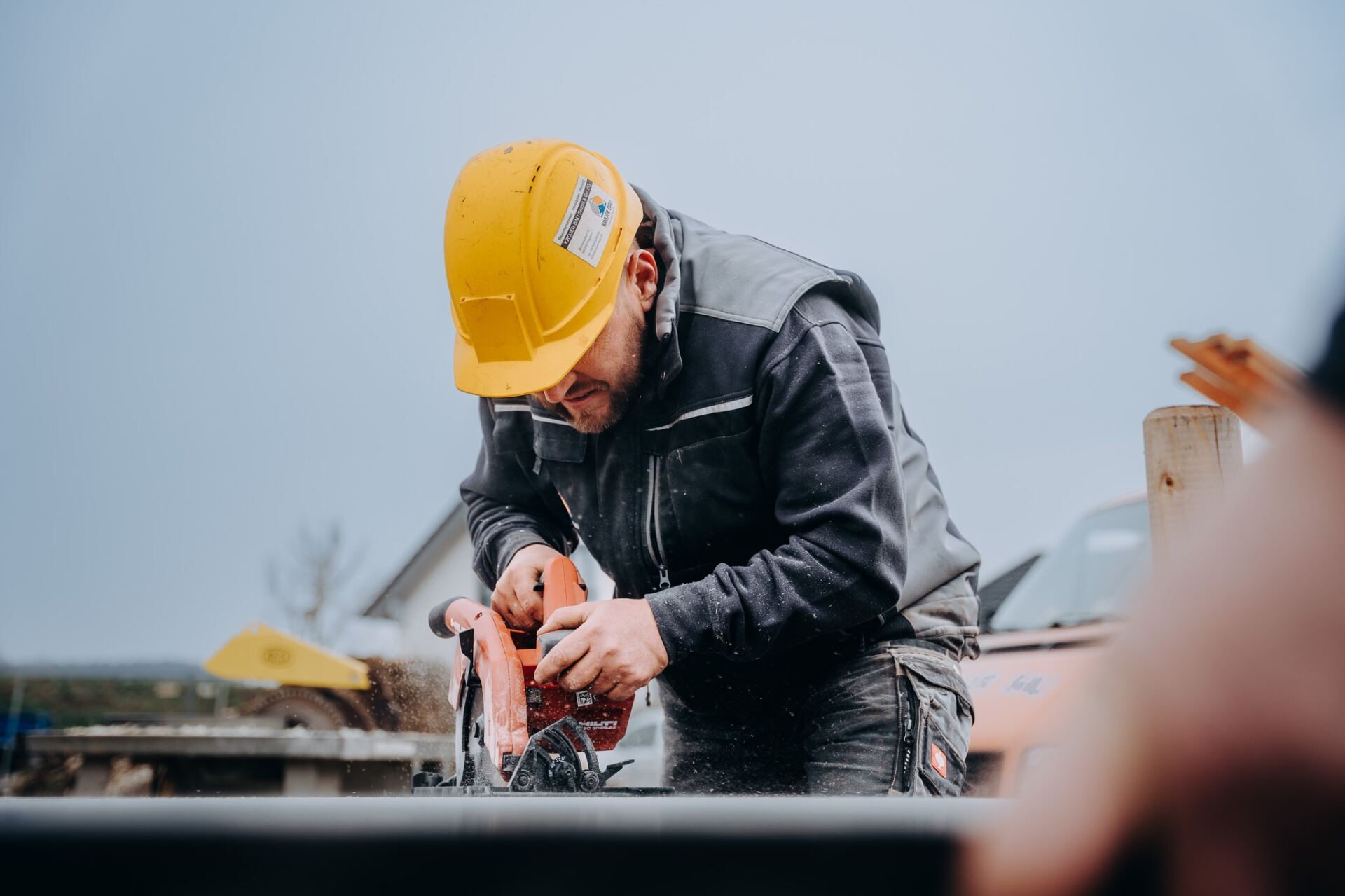 Krojer Bau – Konzentriertes Schneiden mit Hilti-Säge und gelbem Bauhelm