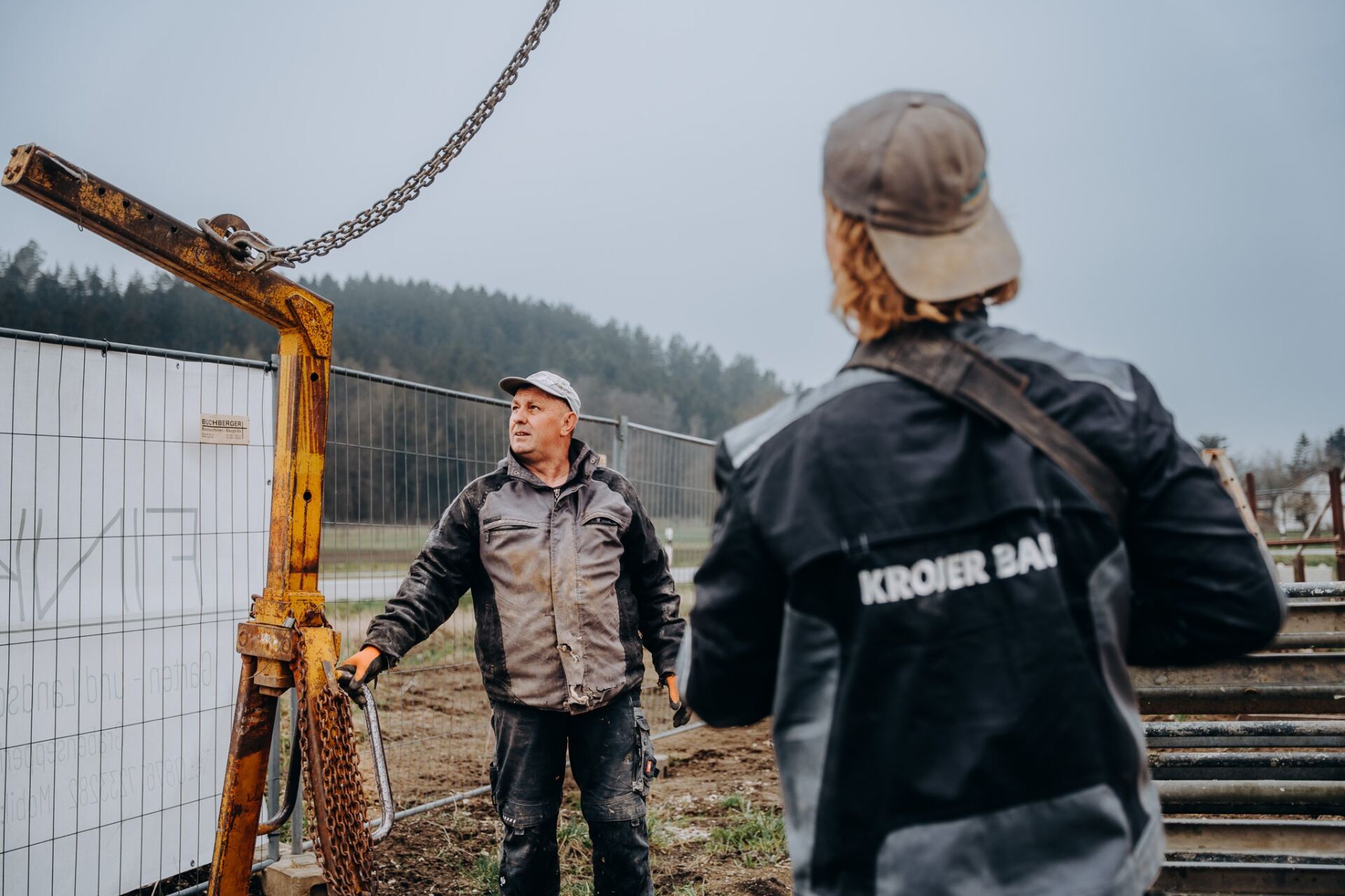 Krojer Bau – Zwei Mitarbeiter koordinieren Lastenkran