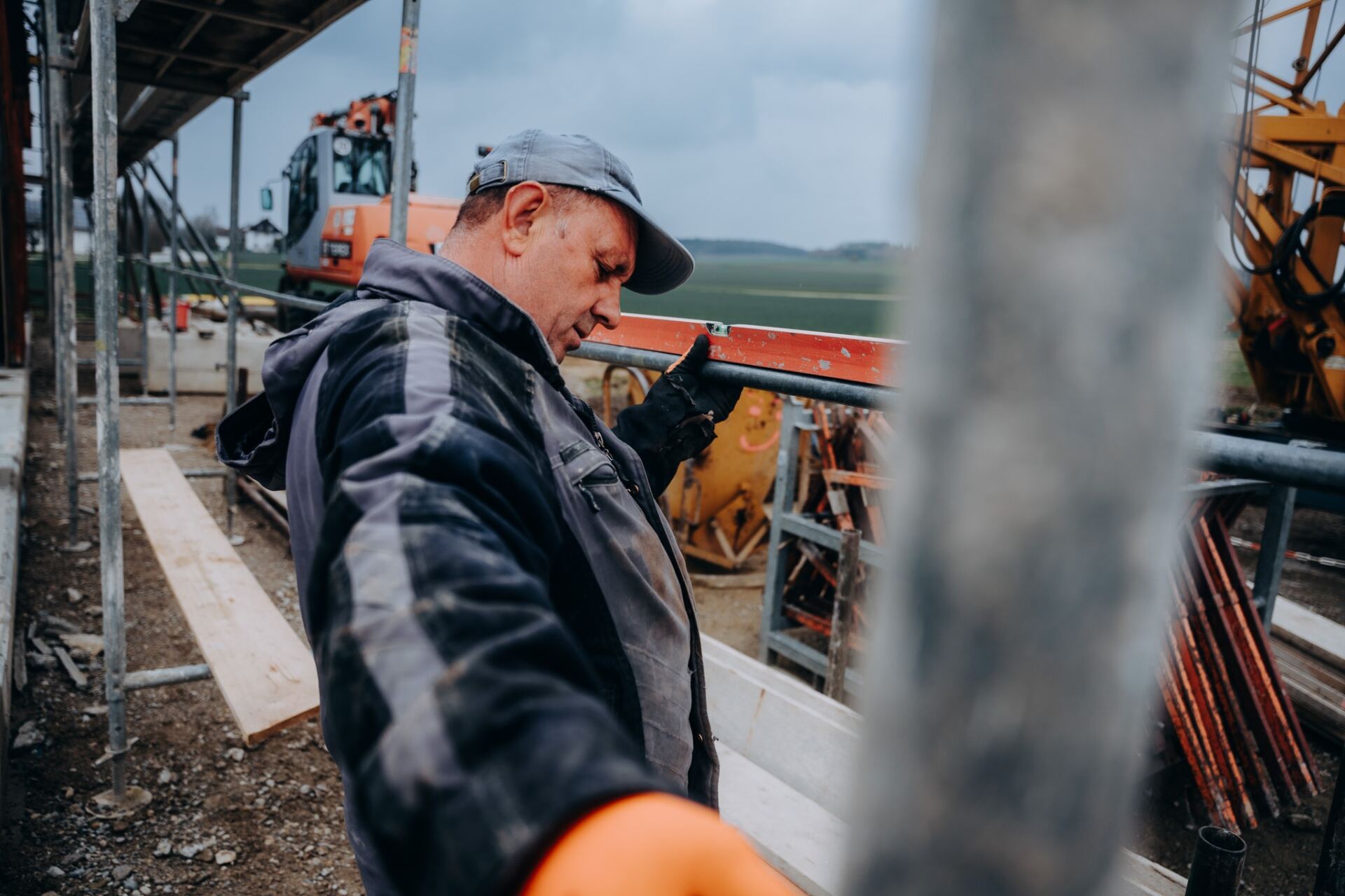Krojer Bau – Wasserwaage prüfen vor Bagger und weitem Feld
