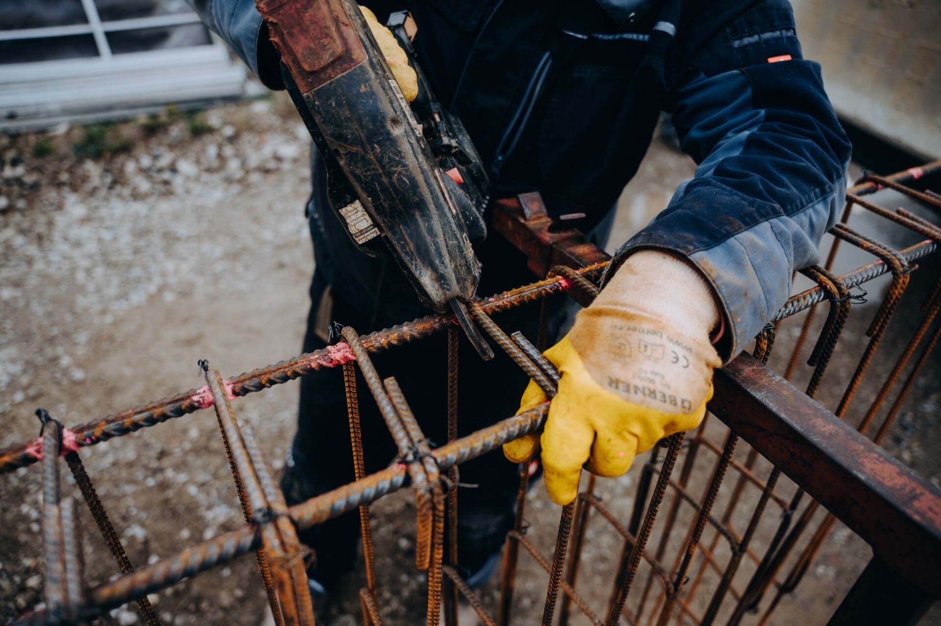 Krojer Bau – Bewehrung binden mit gelben Schutzhandschuhen