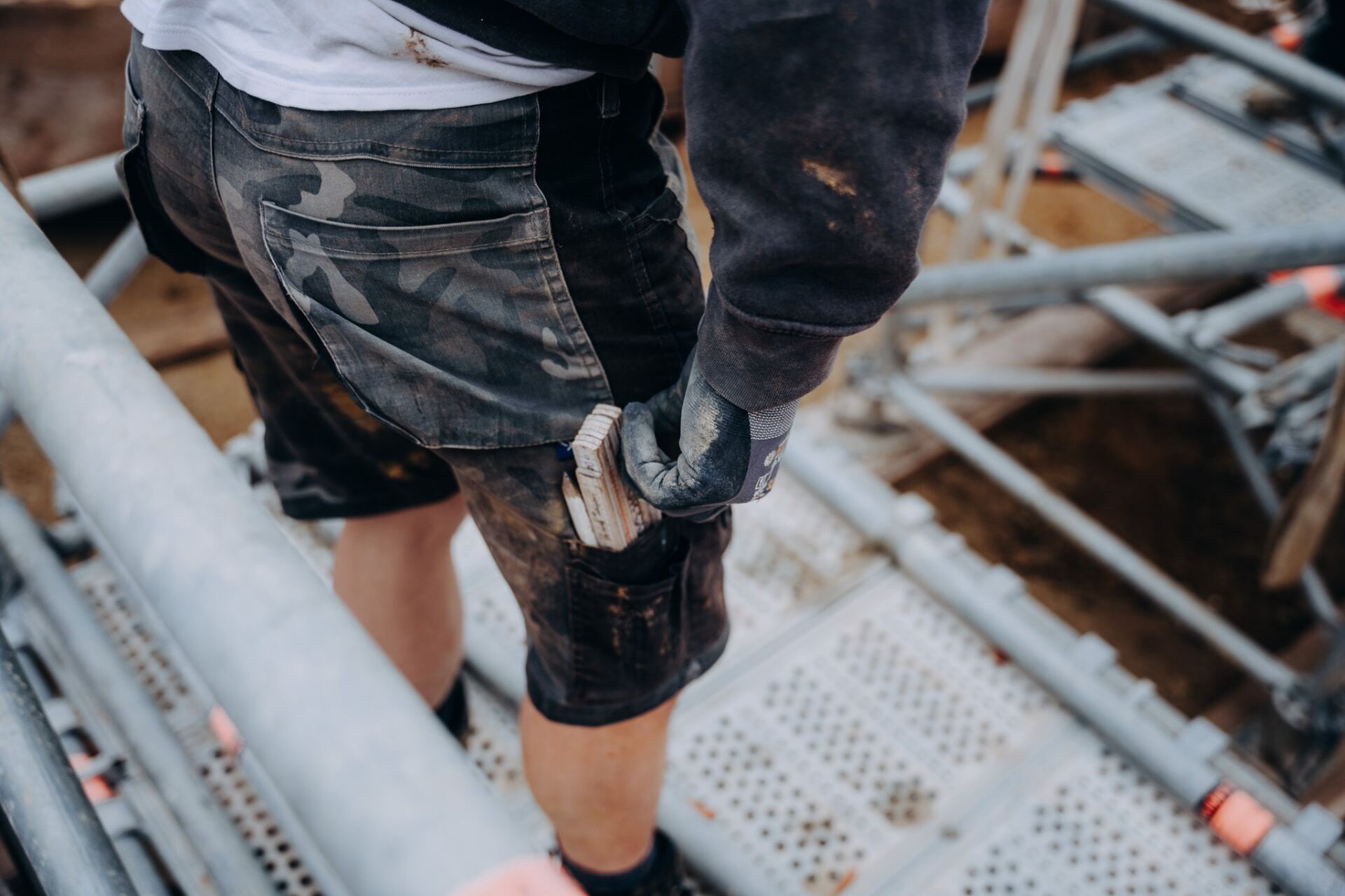 Krojer Bau – Camouflage-Shorts mit Meterstab auf dem Gerüst