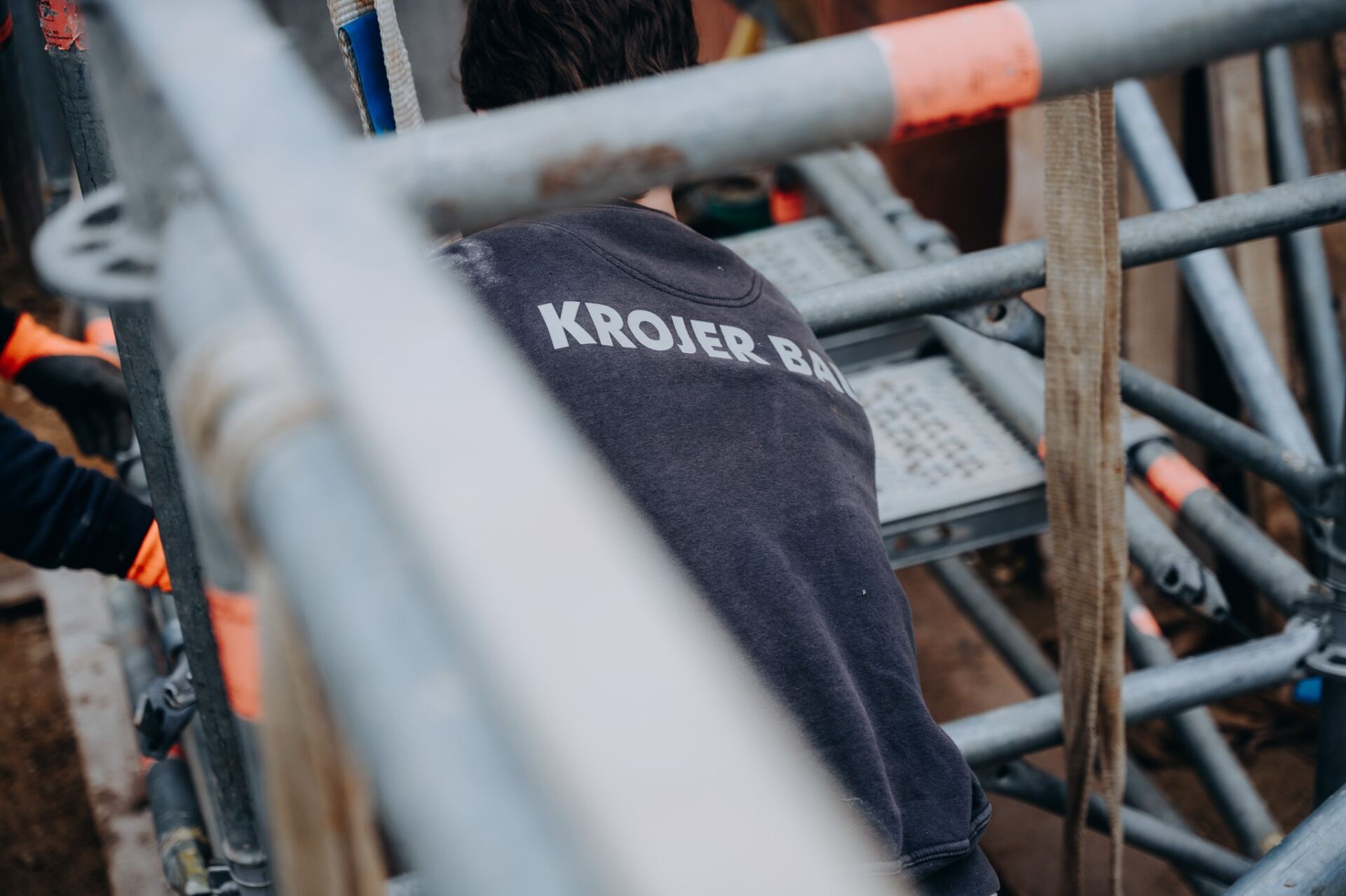Krojer Bau – KROJER BAU Schriftzug auf Pullover im Gerüstausschnitt